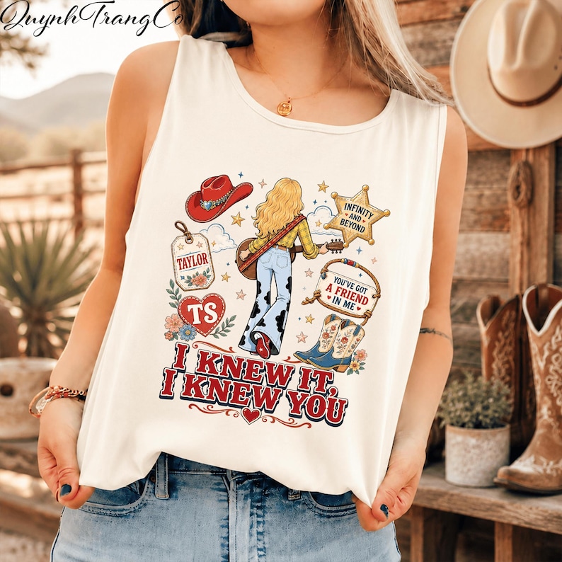 May include: A white sleeveless tank top featuring a graphic print of a blonde person with a guitar, a red cowboy hat, a star badge with text Infinity and Beyond, a tag labelled Taylor, a heart labelled TS, and boots with the text You've Got A Friend In Me.