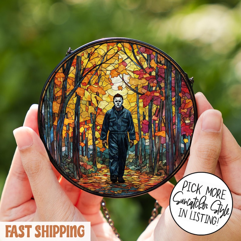 May include: A round stained glass suncatcher featuring a figure in a mask walking through a colorful autumn forest. The suncatcher has a black metal frame and a chain for hanging. Text on the image says "Pick More Suncatcher Style in Listing!"