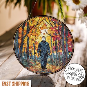 May include: Round stained glass suncatcher featuring a figure in a mask walking through a colorful autumn forest. The artwork has a black metal frame and is suspended by a chain. Text on the image says "Pick More Suncatcher Style in Listing!"