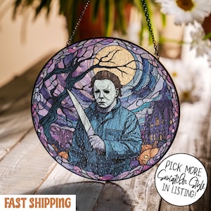 May include: Round stained glass suncatcher featuring a horror movie character holding a knife. The design includes a full moon, a haunted house, and pumpkins, with the text "Pick More Suncatcher Style in Listing!"