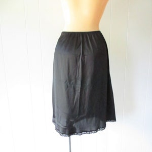 May include: Black slip skirt with a lace trim. The skirt is made of a sheer fabric and has a straight silhouette.