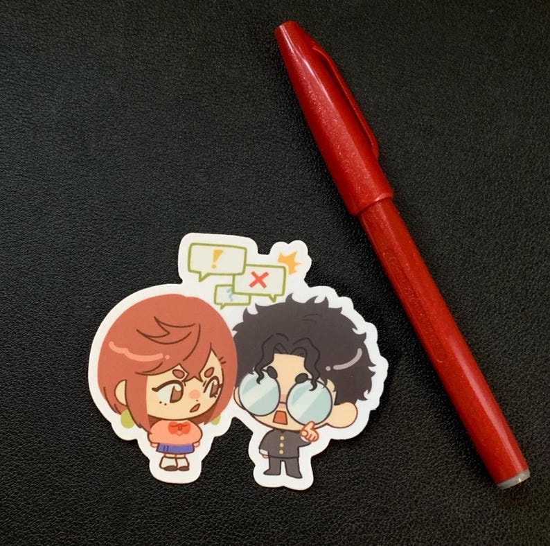 Puede incluir: Una pegatina con dos personajes de dibujos animados con bocadillos. Un personaje tiene el pelo rojo y el otro tiene el pelo rizado oscuro y gafas. Tambi&eacute;n hay un bol&iacute;grafo rojo en la imagen.