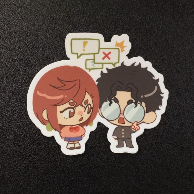 Puede incluir: Una pegatina con dos personajes de dibujos animados. Uno tiene el pelo rojo, una camisa rosa y una falda azul. El otro tiene el pelo rizado oscuro, gafas y un traje negro. Encima de ellos hay bocadillos con un signo de exclamaci&oacute;n y una X.