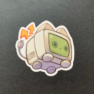 May include: A white and green cartoon cat-shaped computer with a yellow lightning bolt coming out of its tail. The computer has a screen with two green eyes and a small mouth.