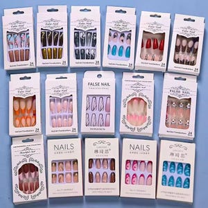 May include: A collection of 24-piece false nail sets in various designs and colours. The sets feature different patterns, including animal prints, abstract designs, and solid colours. The packaging is white with black text and includes the words "False Nail" and "Nail Art Trendsetters".