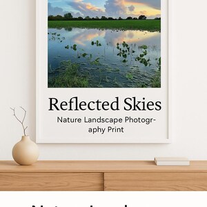 Puede incluir: Una fotografía enmarcada de un paisaje con un reflejo del cielo en un charco de agua. El título de la fotografía es "Reflected Skies" y el texto debajo del título dice "Nature Landscape Photography Print".
