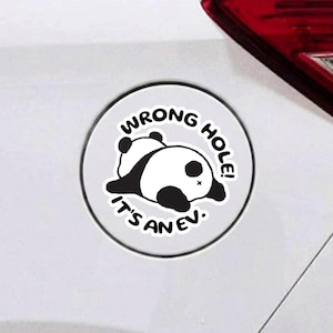 May include: A circular white sticker featuring a black and white illustration of a panda lying down. The text WRONG HOLE! IT'S AN EV. is printed in black capital letters in a curved arc around the panda graphic on the sticker surface.