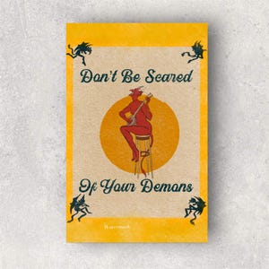 May include: A vintage poster with a yellow background and the text "Don't Be Scared Of Your Demons." The illustration features a red devil playing a banjo on a stool, set against a yellow circle. Small black devil figures are in each corner.