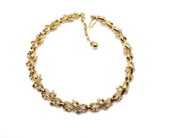 May include: A gold tone necklace with a delicate chain design featuring small clear rhinestones. The necklace has a simple clasp closure.