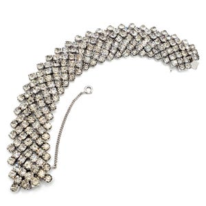 Könnte beinhalten: Ein silberfarbenes Strass-Armband mit einer Kettenverschluss. Das Armband besteht aus mehreren Reihen kleiner, klarer Strasssteine.