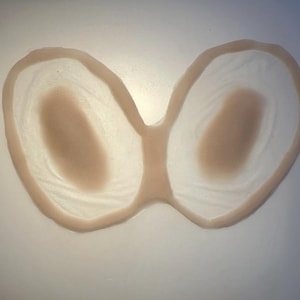 以下が含まれることがあります： ベージュのシリコン製乳房義肢のペア。 形状は涙型で、滑らかでリアルな質感です。