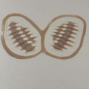 Puede incluir: Un sello de goma marrón con un diseño de mariposa. La mariposa tiene dos alas con un patrón texturizado.