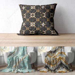 May include: Two white chairs with throw blankets. One blanket is blue and white with a marble pattern. The other blanket is grey and white with a marble pattern. A black and gold pillow with a geometric pattern is on a wooden surface.