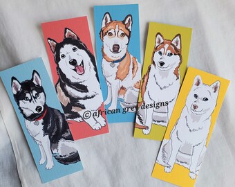 May include: Set of five colorful bookmarks featuring illustrations of different husky dog breeds. Each bookmark has a different colored background and features a different husky dog breed with a unique expression.