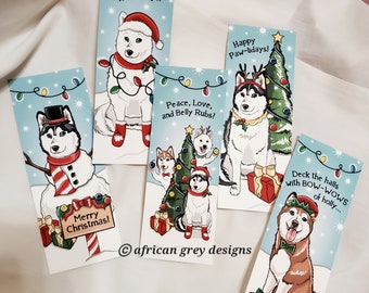 May include: Set of five Christmas-themed greeting cards featuring illustrations of huskies in various holiday scenes. The cards feature festive colors and designs, including a snowman, a Christmas tree, and a reindeer. The text on the cards includes "Happy Howl-idays!" "Peace, Love, and Belly Rubs!" "Happy Paw-lidays!" "Merry Christmas!" and "Deck the halls with BOW-WOWS of holly..."