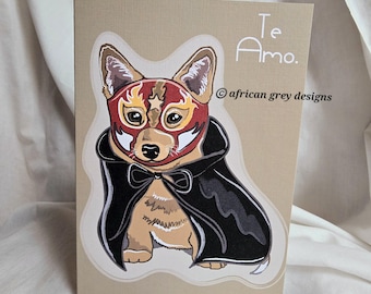 May include: A tan-colored greeting card featuring a cartoon corgi wearing a red and gold wrestling mask and a black cape. The words "Te Amo" are written in white script. The artist's name is also visible.