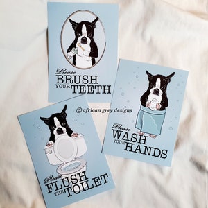 May include: Three blue and white bathroom signs with illustrations of a Boston Terrier dog. The first sign says "Please Brush Your Teeth", the second sign says "Please Wash Your Hands", and the third sign says "Please Flush The Toilet".