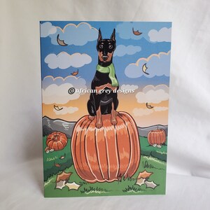 May include: A black and brown Doberman Pinscher dog wearing a green scarf sits on top of a large orange pumpkin. Two smaller pumpkins are in the background. The image has a fall theme with leaves falling from the sky.