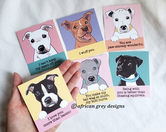 May include: Set of six illustrated greeting cards featuring different dog breeds with humorous captions. The cards are printed on white cardstock with a colorful background and feature a dog breed with a playful expression. The captions include "I can't keep my paws off you", "I wuff you", "You are paw-sitively wonderful", "You make my tail wag so much, my butt hurts", "Being with you is better than chasing squirrels", and "I love you more than bacon!"