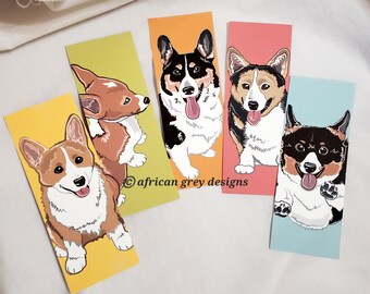 May include: Four colorful bookmarks featuring different illustrations of corgis. Each bookmark has a different background color: yellow, orange, pink, and blue. The text "african grey designs" is printed on the bottom of the bookmarks.