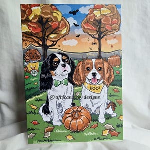 May include: A canvas print featuring Cavalier King Charles Spaniels in a fall scene. Two dogs are in the foreground, one with a green bow tie and the other with a "BOO!" bandana. A pumpkin and autumn leaves are on the grass.