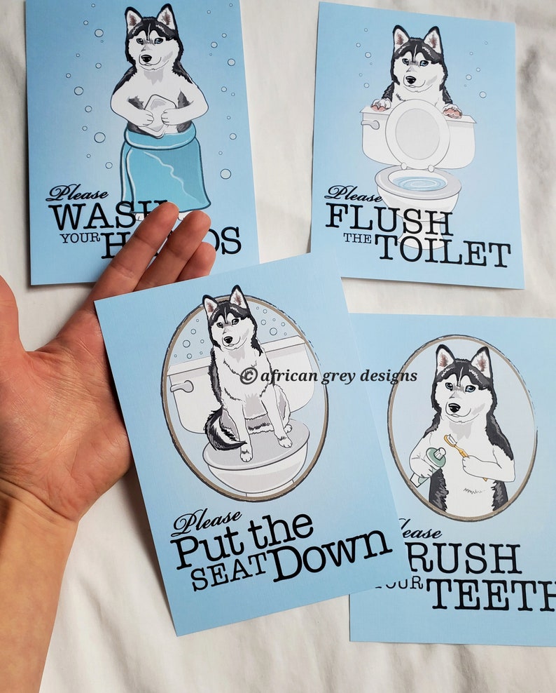 May include: Four blue signs with a cartoon husky dog on each. The signs have instructions for bathroom etiquette. The first sign says "Please Wash Your Hands". The second sign says "Please Flush The Toilet". The third sign says "Please Put The Seat Down". The fourth sign says "Please Brush Your Teeth".