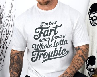 May include: White t-shirt with the text "I'm One Fart away from a Whole Lotta Trouble" in a dark gray, slightly distressed font. The shirt is a classic crew neck style.