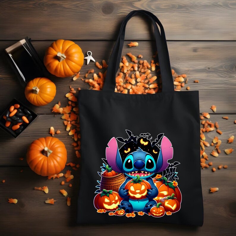 May include: A black tote bag featuring a graphic print of a blue alien character holding a glowing jack-o'-lantern, surrounded by several other pumpkins, a woven basket, and a background of black bats and spider webs against a dark backdrop.