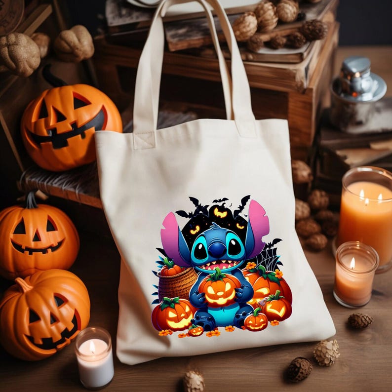 May include: A cream-coloured canvas tote bag featuring a colourful graphic of a blue alien character holding a glowing jack-o'-lantern, surrounded by several other pumpkins, bats, and a spider web, with two sturdy shoulder straps at the top.