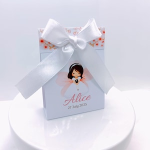 Puede incluir: Una caja de regalo blanca con un estampado floral y un lazo de satén blanco. La caja presenta una ilustración de dibujos animados de una niña con un vestido blanco y el nombre "Alice" con la fecha "27 de julio de 2025".