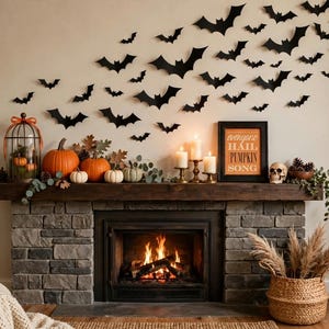 Pode incluir: Uma lareira de pedra decorada para o Halloween com abóboras laranja, cabaças brancas, uma gaiola, três velas acesas, um crânio e uma moldura com o texto "everyone hail PUMPKIN SONG". Morcegos de papel preto estão dispostos na parede acima.