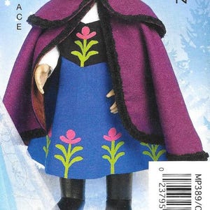 Peut inclure: Une poup&eacute;e v&ecirc;tue d'une cape violette avec une bordure noire et d'une robe bleue avec des motifs floraux roses et verts. La poup&eacute;e porte des bottes noires. L'image comprend le texte "ACE" et un code-barres.