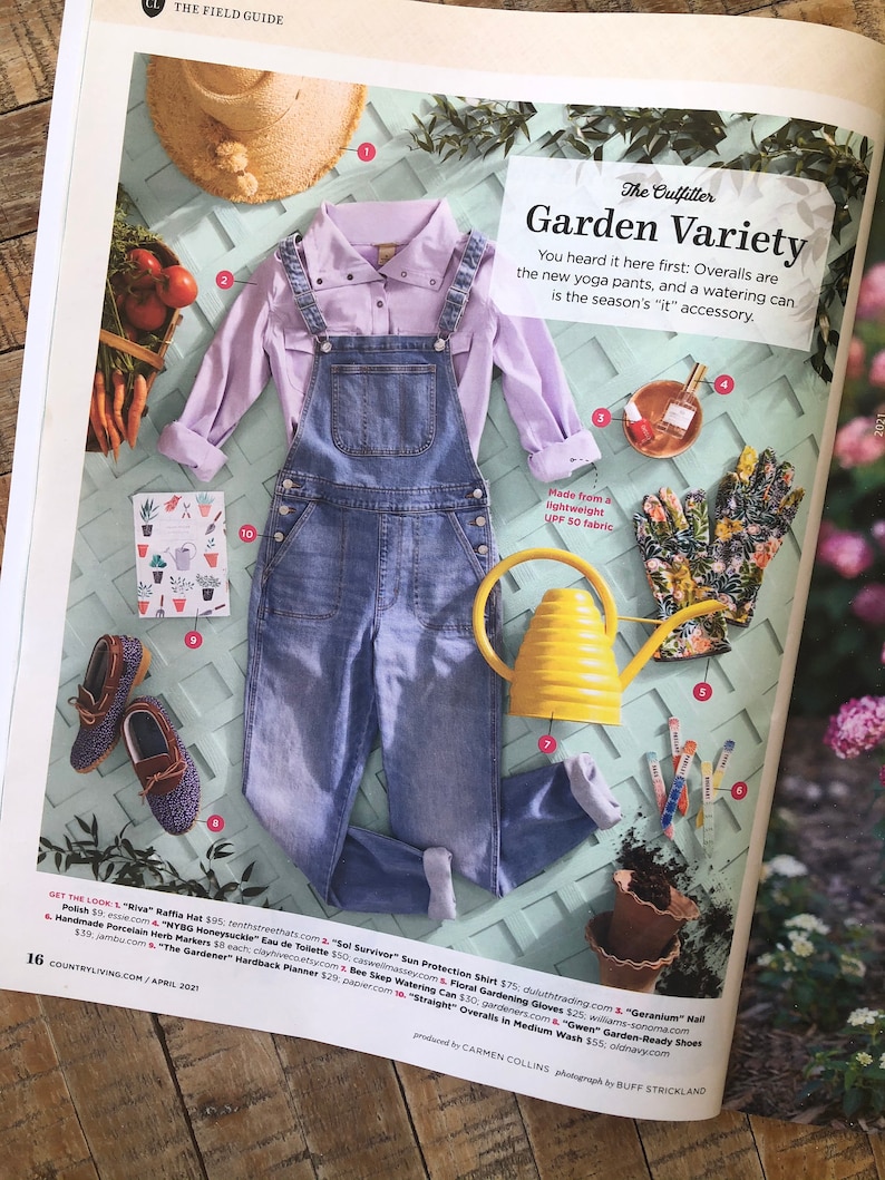 May include: A flat lay of gardening essentials, including a pair of blue denim overalls, a light purple button-down shirt, a yellow watering can, a pair of brown leather shoes, a floral gardening glove, and a set of colorful gardening tools. The text "Garden Variety" is written in a white box.