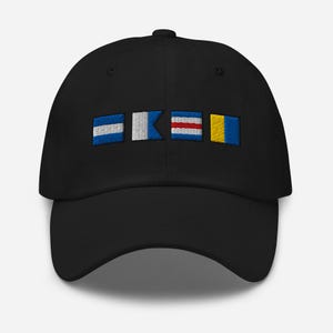 Puede incluir: Gorra de béisbol negra con banderas de señales náuticas bordadas en azul, blanco, rojo y amarillo. La gorra tiene una visera curva y una correa ajustable. Un accesorio elegante.