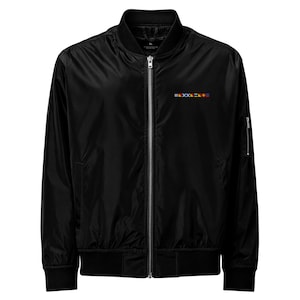 Könnte beinhalten: Schwarze Bomberjacke mit Reißverschluss, gerippten Bündchen und einem kleinen gestickten Design auf der Brust. Die Jacke hat einen klassischen Bomber-Stil mit einem schlanken, minimalistischen Design. Die Jacke hat eine kleine Tasche am linken Ärmel.