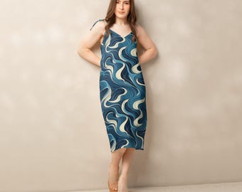 Könnte beinhalten: Midikleid mit blau-weißem Wellenmuster. Das Kleid hat einen V-Ausschnitt und Spaghettiträger. Hergestellt aus leichtem Stoff, ideal für warmes Wetter. Eine stilvolle und bequeme Wahl für verschiedene Anlässe.