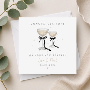 May include: A square greeting card featuring the text CONGRATULATIONS ON YOUR VOW RENEWAL, Lisa & Paul, and 05.07.2026. The design includes two illustrated champagne coupes, each tied with a black ribbon, set against a white background.