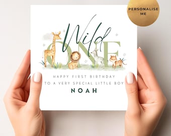Op de afbeelding: Een witte verjaardagskaart met een junglethema. De kaart bevat het woord "Wild" in groen schrift, met "ONE" in een blokletter. Illustraties van een giraffe, leeuw, zebra en tijger zijn inbegrepen. De tekst luidt "Happy First Birthday to a Very Special Little Boy NOAH."