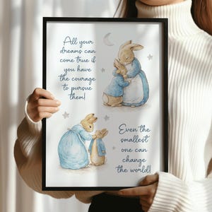 May include: A framed print with illustrations of rabbits in blue and tan outfits. The print includes inspirational quotes in cursive script, such as "All your dreams can come true." The artwork is set within a black frame.