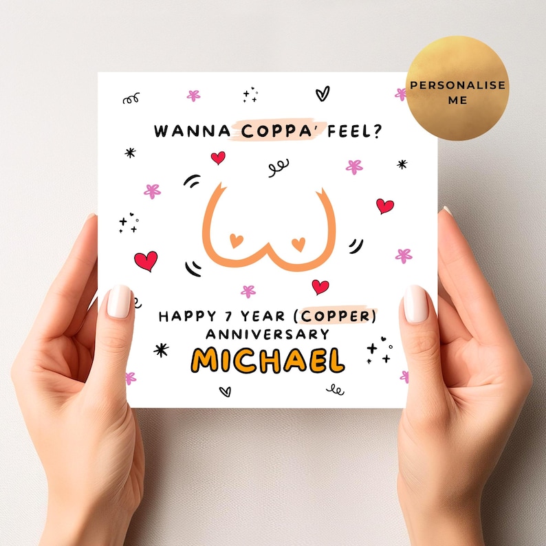 May include: A white greeting card held by hands, featuring the text "WANNA COPPA' FEEL?" and "HAPPY 7 YEAR (COPPER) ANNIVERSARY MICHAEL". The card has a cartoon illustration of breasts and decorative hearts and stars.