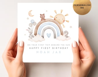 May include: A square greeting card with a watercolor illustration of a rainbow, sun, moon, and clouds. The card reads "ON YOUR FIRST TRIP AROUND THE SUN HAPPY FIRST BIRTHDAY NOAH JAX". A gold circle says "PERSONALISE ME".