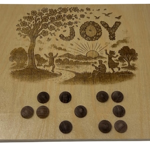 May include: Wooden board with a laser-etched design featuring a tree, figures, and the word "JOY". Dark brown wooden game pieces are arranged on the board. The board is approximately 12 inches square.
