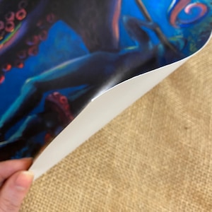 May include: A close-up of a colorful painting of an octopus with tentacles. The octopus is painted in shades of blue, purple, and pink. The background is a dark blue with hints of green.