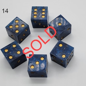 May include: A set of five six-sided dice with a deep blue marbled finish and gold-colored pips. The number 14 is printed in the top left corner, and the word SOLD is overlaid in red across the center of the dice arrangement.