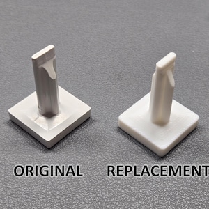 May include: Two white plastic parts, one labeled "ORIGINAL" and the other "REPLACEMENT". Each part has a square base and a vertical post with a hook-like top. The "ORIGINAL" part is light gray, while the "REPLACEMENT" part is white.