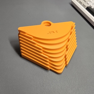 May include: A stack of bright orange, fan-shaped objects with a small hole at the top. The objects have a curved edge and are stacked neatly. The text "2 1/2" is printed on the top object.