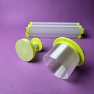 May include: A set of kitchen tools including a circular plunger cutter with a textured base, a larger cylindrical cutter with a lime green rim, and several rectangular strips with lime green ends, all featuring translucent plastic components.