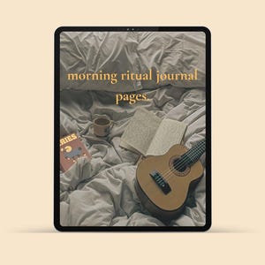 Op de afbeelding: Een tabletscherm met een afbeelding van een verfrommeld lichtgrijs bedsprei met een open dagboek, een kleine keramische mok, een boek met een ram-illustratie en een akoestische gitaar. De tekst morning ritual journal pages staat in het geel gecentreerd.