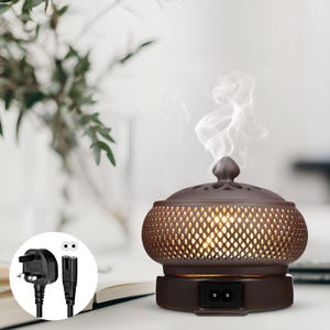 May include: A brown ceramic essential oil diffuser with a lattice design and a small knob on top. The diffuser is emitting a wisp of white vapour. A black power cord is shown in the lower left corner.