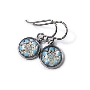 May include: A pair of silver earrings featuring a blue and gold floral design. The earrings are made from titanium and have a hook fastening.